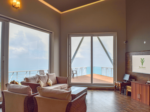 Lounge area at Ibex Resorts, Coonoor (Tapas) featuring wooden furniture, french windows and good lighting.