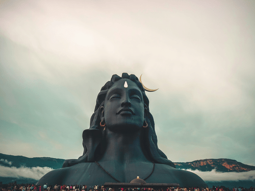 A close-up view of the Adiyogi statue set against a soft cloudy sky.