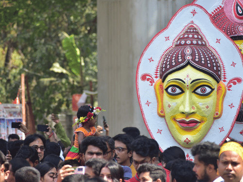A procession on a road with many people carrying busts on a pole during the Bengali New Year in Kolkata