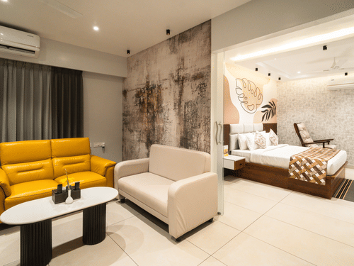 An image of a room with a plush bed in the bedroom and sofas placed around a coffee table in the living room - MGM Whispering Meadows