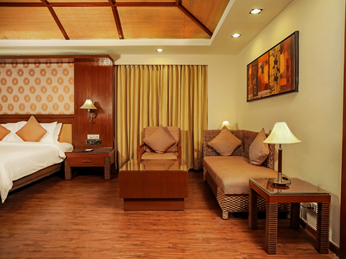 A bedroom with a king bed and a sitting area with wall mounted painting.
