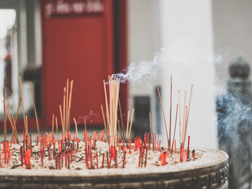 Incense sticks in a sand pit and are lit 