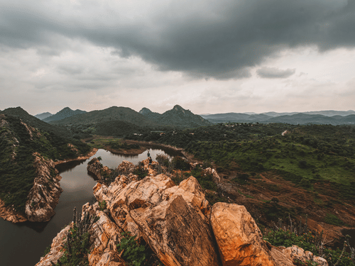 Nature with a small steam running on the left and greenery and hills in the background