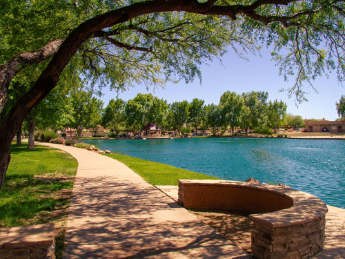 An overview of Matariya Talav with a walking path next to the pristine lake and tree covering on the side, as seen during the day.