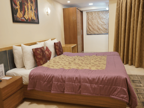 Double bedroom with bedside table and storage units at VITS Kamats Resort, Silvassa