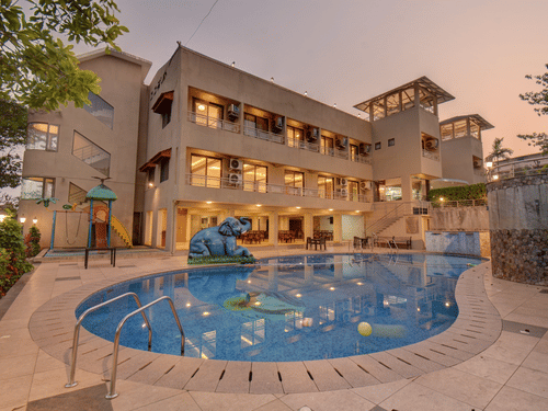 Evening view of illuminated hotel facade and pool at VITS Lonavala.