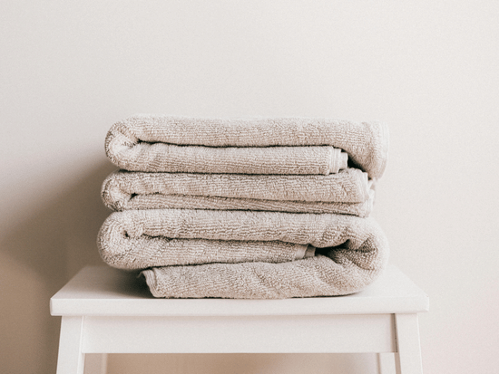 A few white-coloured towels neatly folded and kept on a stool.