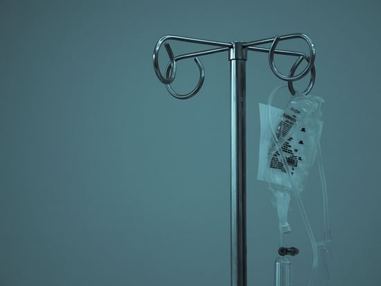 a close up shot of an IV bag hung with blue-green paint on the wall