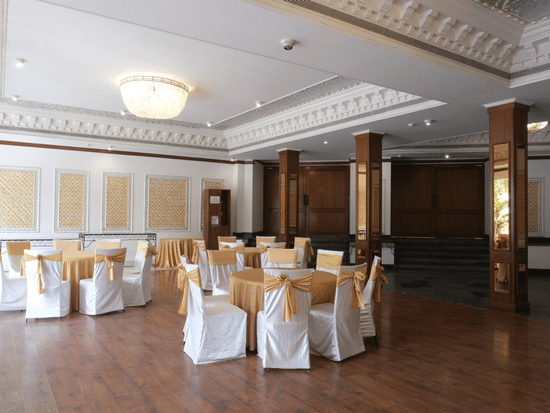 The refined Jal Mahal event venue featuring round dining tables, elegant chair décor, chandeliers, and classic interiors prepared for wedding receptions and family gatherings | Clarks Amer, Jaipur