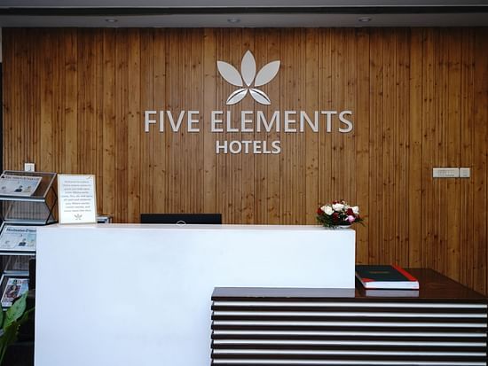 An image of a reception lobby featuring a desk featuring a welcome note, a flower bouquet, and a shack full of newspapers and magazines at Five Elements Hotels North Avenue, Delhi