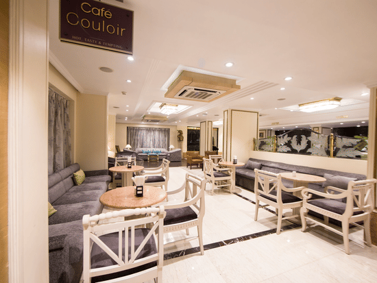 Cafe Couloir at Hotel Bawa International, Vile Parle featuring a dining area with couch and sofa chairs with tables in each setting.