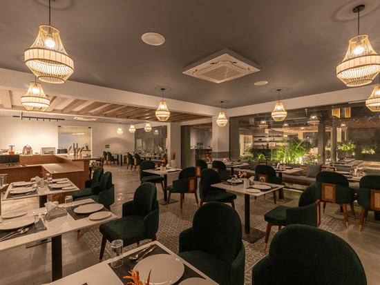 Multi-cuisine restaurant with tables laid out for guests and stylish ceiling lights at Sibaya Courtyard By Stone Wood Premier.