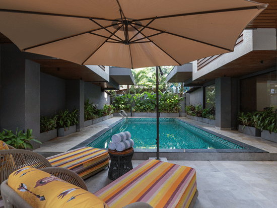 Outdoor central swimming pool with sun loungers, parasols, and courtyard architecture at Sibaya Courtyard By Stone Wood Premier.