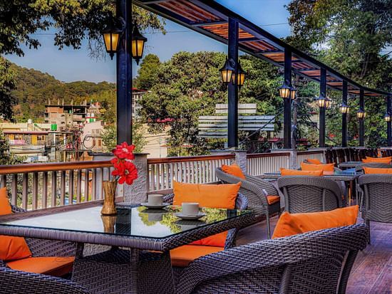 A rooftop dining area with scenic mountain views, decorated with stylish chairs and tables - Vinsober Monal, Nainital