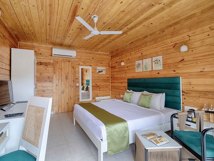A spacious bedroom with a high wooden ceiling, teal headboard, and green accents, complemented by natural light and modern furnishings - Aralea Beach Resort by Stone Wood, Morjim