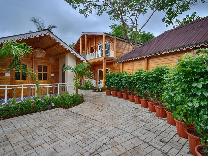 Pathway leading to tropical resort cabins with potted plants and palm trees Aralea Beach Resort by Stone Wood, Morjim