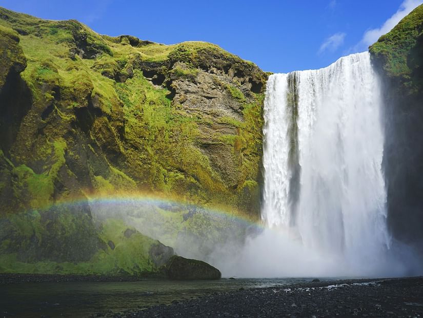 A rainbow arching across a waterfall, creating a vibrant spectrum of colours against the cascading water