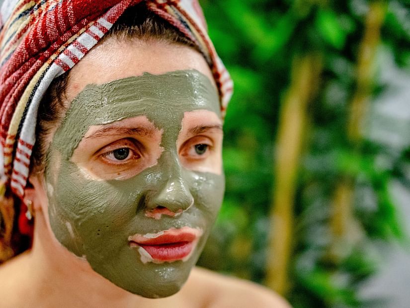 A close up shot of a woman wearing a towel on her head and a face mask on her face.
