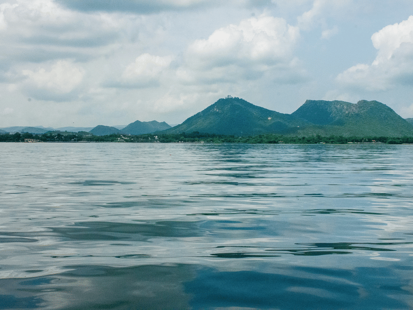 Rippling Fateh Sagar Lake water with distant islands and hills under bright sky in Udaipur