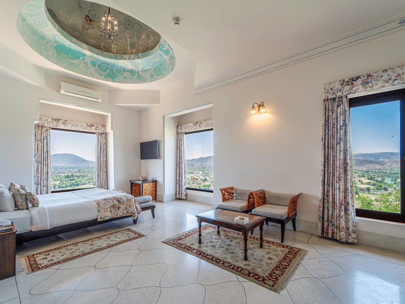 A regal suite showcasing a hand-painted domed ceiling, traditional rugs, and multiple viewing windows - Fateh Garh, Udaipur