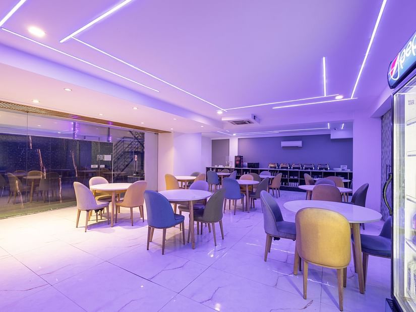 An LED-lit restaurant with chairs and tables at Hotel Bawa, Gurgaon.