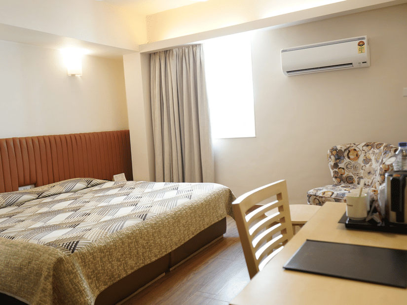 Modern guest room with a queen bed, workspace, and cosy seating area at Hotel Diplomat.
