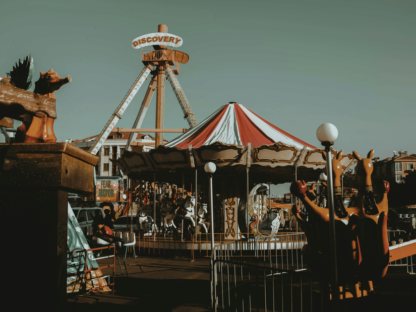 An amusement park's rides with a carousel in the centre and blue sky in the background