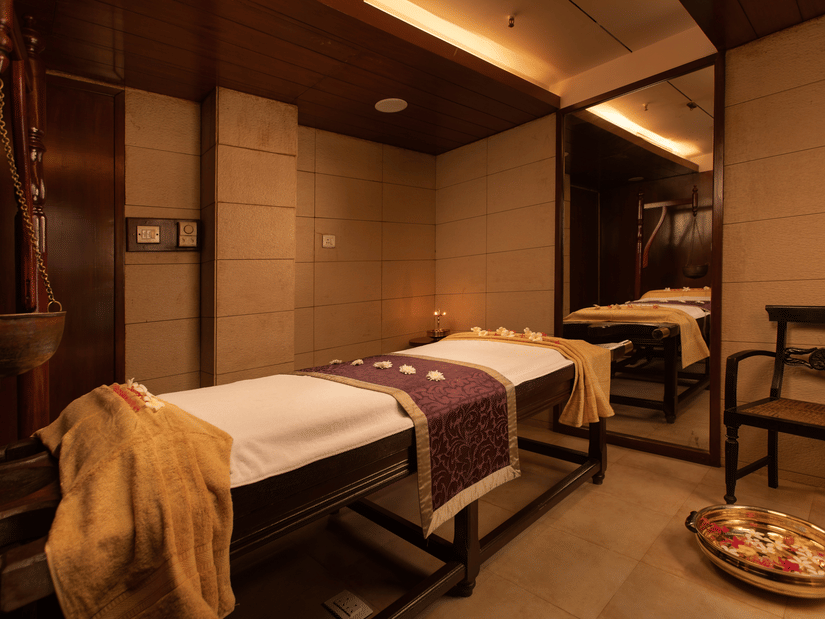 A massage table in the Myra Spa at Kenilworth Resort & Spa, Goa, adorned with decorative towels and positioned in front of a mirror for a relaxing spa experience.