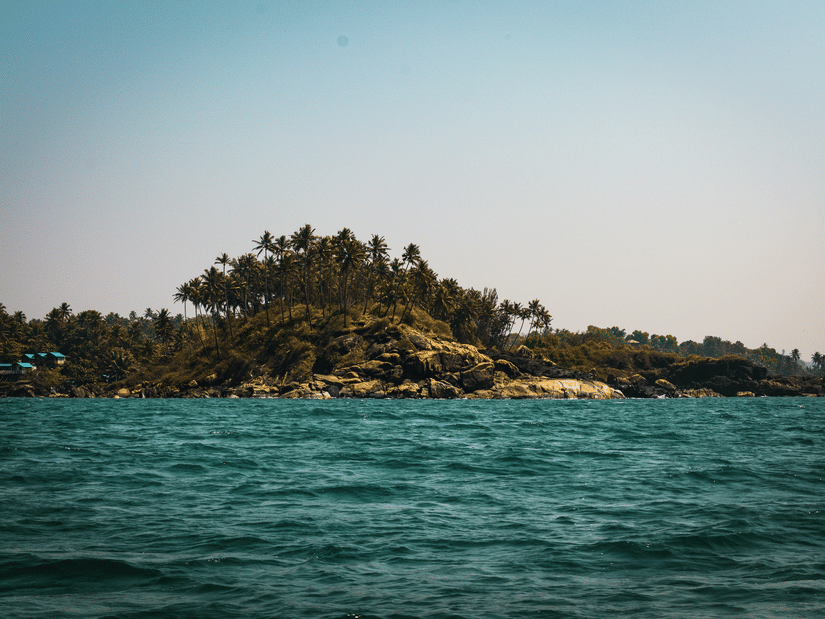 A view from the Arabian Sea of Palolem Beach in the distance with trees also seen. This beach is one of the best attractions in South Goa.