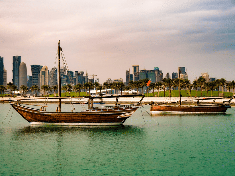 A view of two boats in a greening waterbody with a cityscape in the background at Gewan Island Crystal Walk.