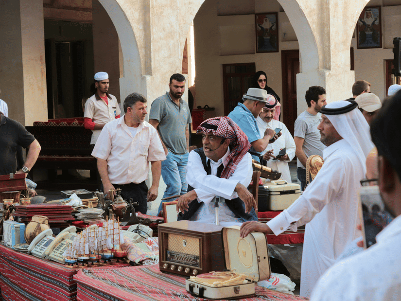 A vibrant Souq Waqif in Qatar with people moving from one stall to another shopping.