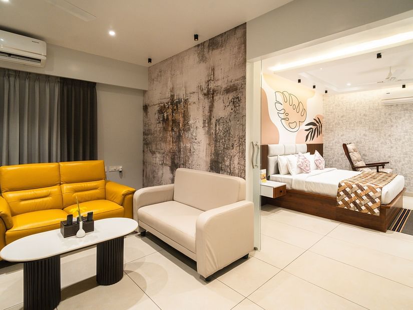 An image of a room with a plush bed in the bedroom and sofas placed around a coffee table in the living room - MGM Whispering Meadows