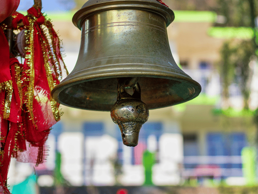 Sacred temple bell tied with prayer threads at a temple