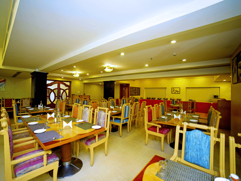 Indoor dining area with wooden tables and chairs at Raj Park Hotel, Tirupati.
