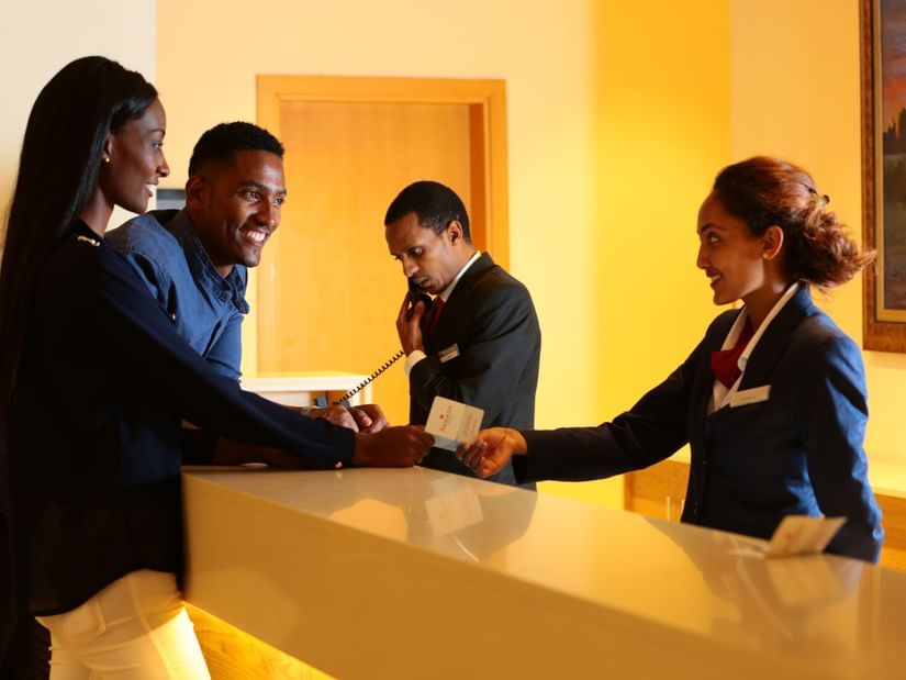 An overview of the reception area with a staff member speaking to two customers - Ramada by Wyndham Addis, Addis Ababa.