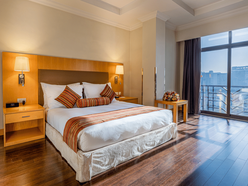 A well-lit, luxurious hotel room with a king-size bed, side tables and lamps at Ramada by Wyndham Addis, Addis Ababa.