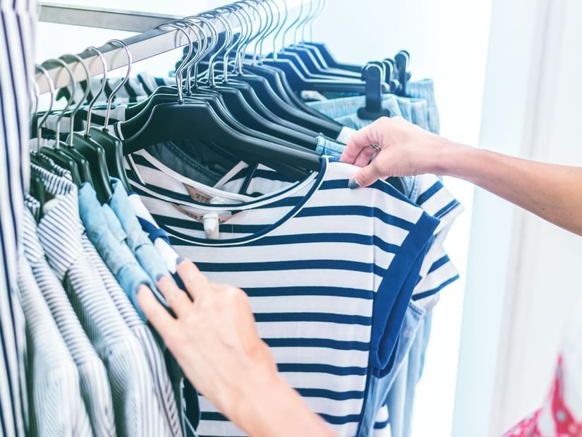 A close up shot of a person checking clothes to buy from a shop.