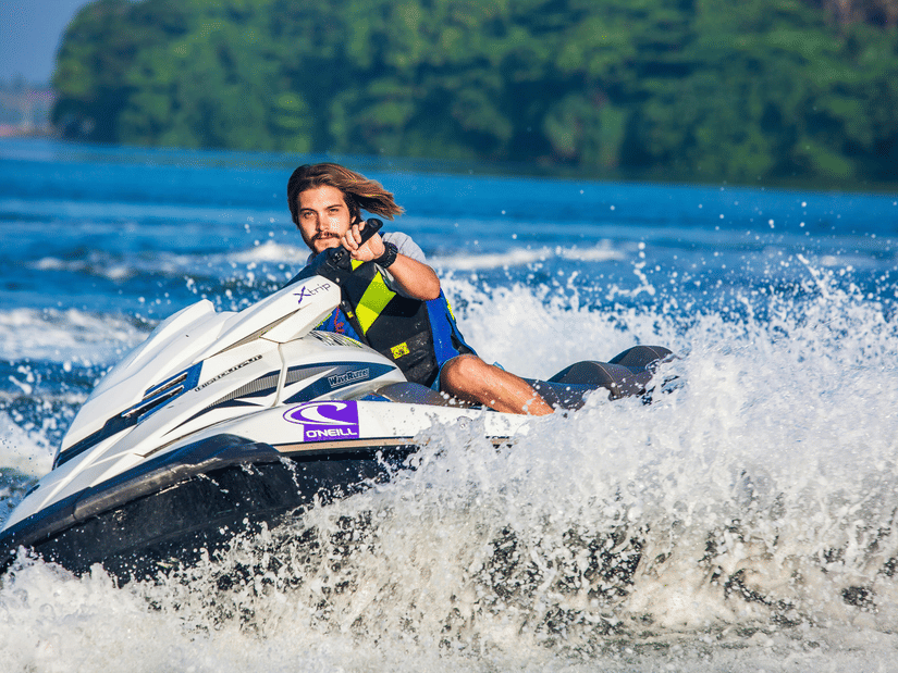 A person wearing a safety harness riding a jet ski across the sea.
