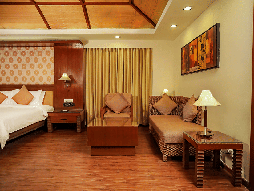 A bedroom with a king bed and a sitting area with wall mounted painting.
