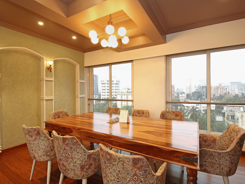 A banquet hall with chairs arranged around a table, featuring large windows that offer a view outside