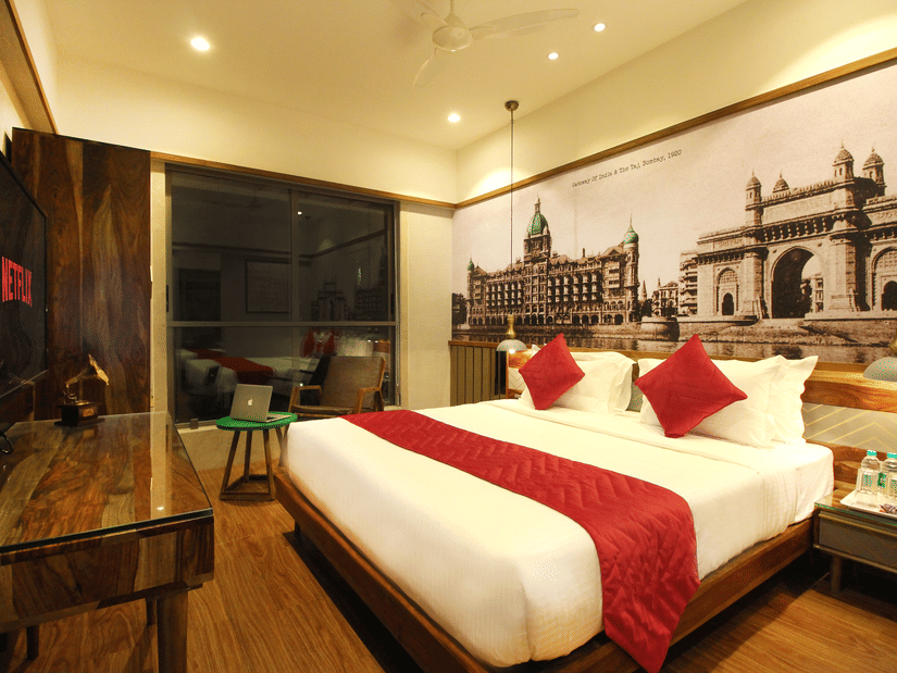 An overview of the 2 Bedroom Suite with a double bed, side tables, a tv, an expansive window overlooking the city in Khar area.