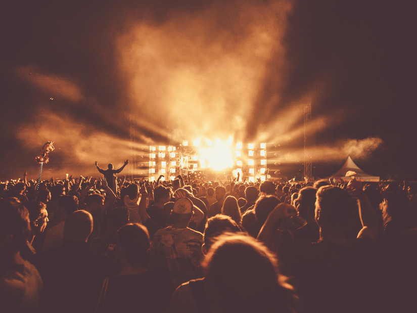 Excited audience enjoying a live performance as powerful stage lights beam across the festival grounds