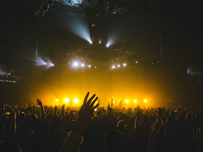 Packed crowd immersed in a live music show featuring vibrant stage lighting, visual effects, and a high-energy atmosphere