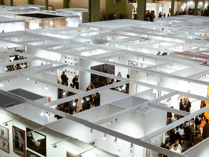 An aerial view of a trade show with many stalls and people walking amongst them.