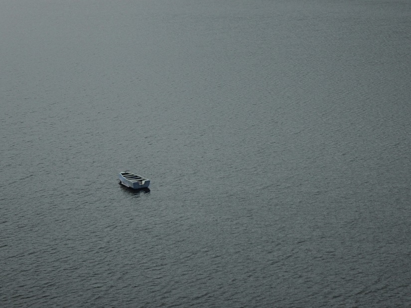 A view of a empty solitary boat flowing on Siliserh Lake with waves seen on the river body.