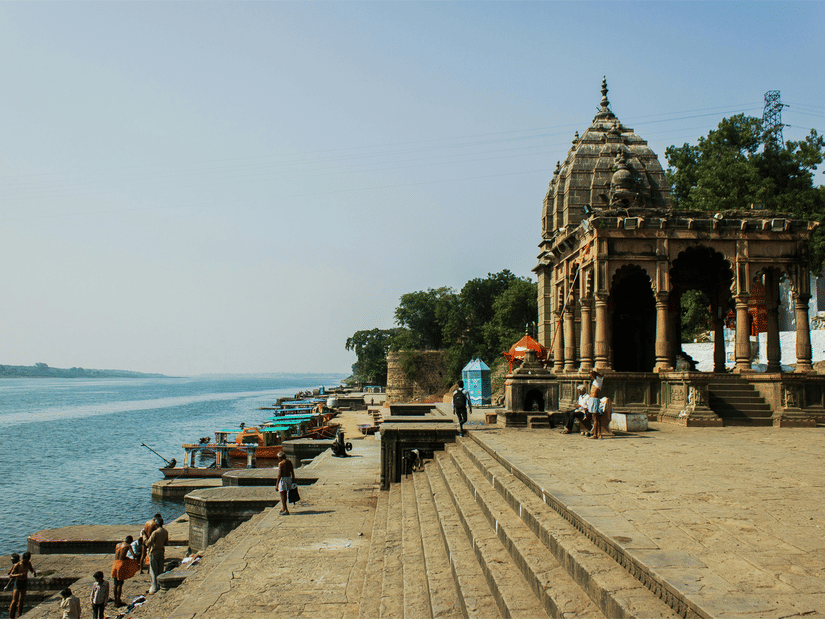 A view of the Narmada River on the left and steps leading to the river on the right hand side with a temple on it. The number of Narmada Parikrama walking days differ to your pace, it might take 200 days to 3 years, 3 months and 13 days.