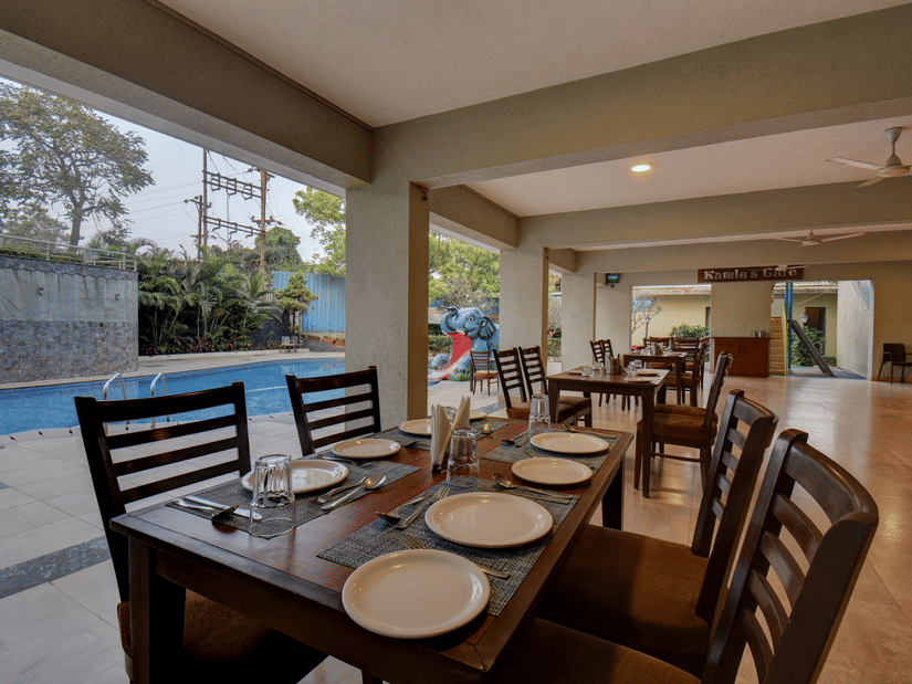 Indoor dining area with neatly arranged tables and poolside view at VITS Lonavala.