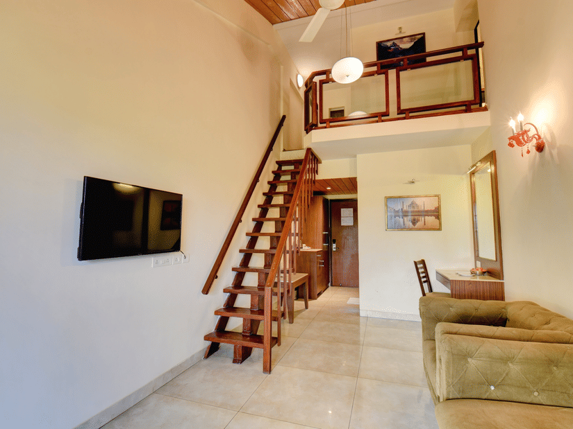Loft-style suite with wooden staircase and modern wall-mounted TV at Duplex Room inside VITS Lonavala.