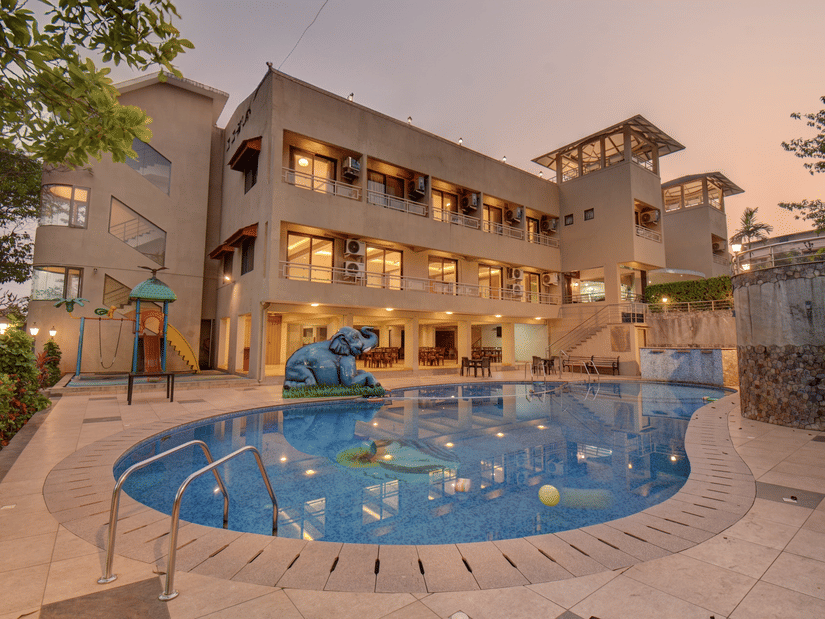 Evening view of illuminated hotel facade and pool at VITS Lonavala.