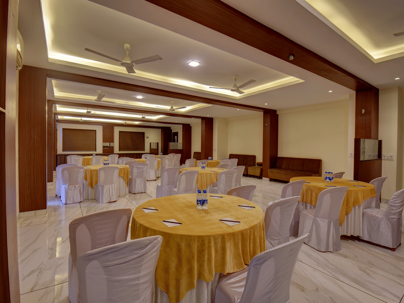 A banquet hall with round tables and decorative ceiling lights at VITS Lonavala.